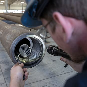 A worker inspecting a pipe with a magnifying glass
